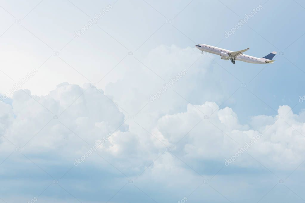 Commercial airplane flying over bright blue sky and white clouds