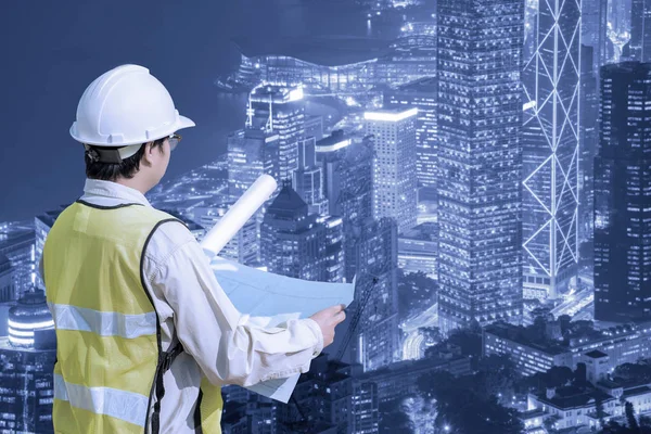 Инженер-строитель проверяет чертеж строительства с современным городским пейзажем — стоковое фото