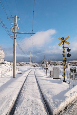 Railway track for local train with white snow fall in Japan clipart