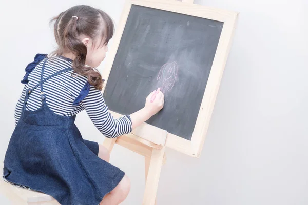 Gelukkig Aziatisch meisje kind tekenen cartoon met krijt op blackboard voor het leren thuis — Stockfoto