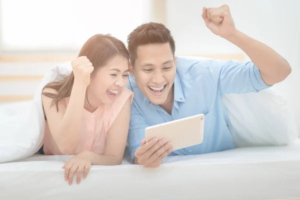 Família feliz, amantes do casal asiático gostam de animar e assistir futebol esporte transmissão ao vivo em tablet inteligente . — Fotografia de Stock
