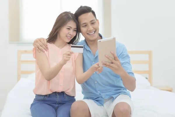 Onnellinen perhe, aasialainen pari ystäville nauttia käyttäen älykäs tabletti online-ostoksia yhdessä makuuhuoneessa . — kuvapankkivalokuva
