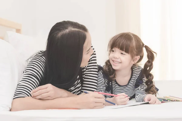 Glückliche Familie im Schlafzimmer, asiatische Mutter bringt ihrer Tochter das Lernen für die Vorschule bei. — Stockfoto