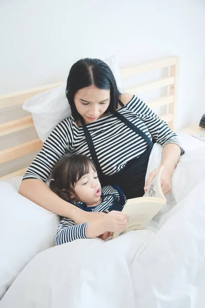 Boldog szerető család fiatal ázsiai anya lánya, egy ágy idő story könyvet olvasott tanítás — Stock Fotó