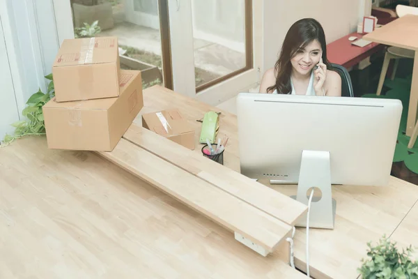 Jovem empreendedora trabalhando no computador inteligente enquanto conversa com seu cliente no escritório em casa — Fotografia de Stock