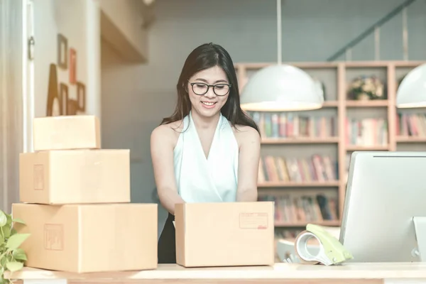 Joven emprendedora empacando el producto en la caja para sus clientes después de recibir la orden en la oficina en casa . —  Fotos de Stock