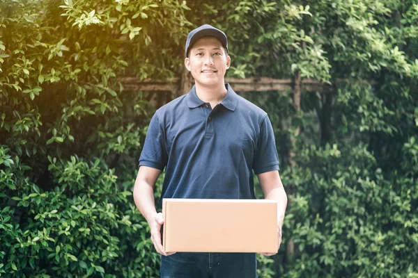 Bonito jovem asiático entrega homem sorrindo enquanto segurando uma caixa de papelão entrega para seu cliente . — Fotografia de Stock
