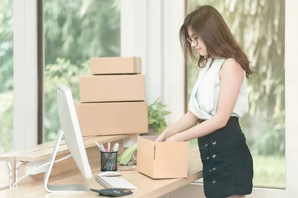 Jovem empresário embalagem produto na caixa para seus clientes após recebeu ordem no escritório em casa . — Fotografia de Stock