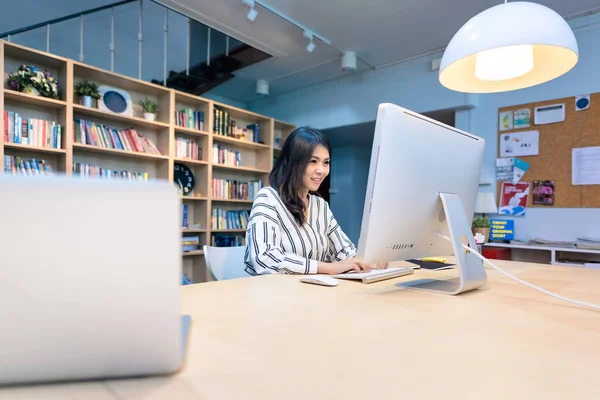 Ortak çalışma ofisinde akıllı bilgisayar üzerinde çalışan genç iş girişimci.