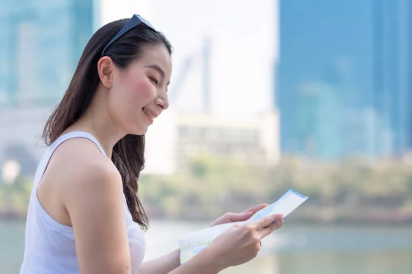 Beautiful asian tourist woman looking at map for searching location of landmark — Stock Photo, Image