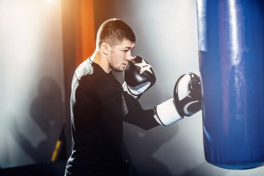 Yoğunlaşmış profesyonel bir boksör kum torbasına vurur..