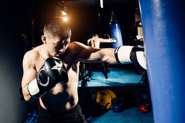 Yoğunlaşmış profesyonel bir boksör kum torbasına vurur..