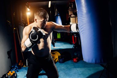 Yoğunlaşmış profesyonel bir boksör kum torbasına vurur..