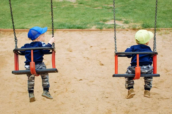 2 irmãos gêmeos andam juntos em um balanço, 1-2 anos — Fotografia de Stock