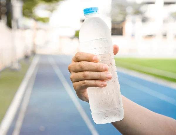 Cold water in transparent bottle is holding in one hand for refr