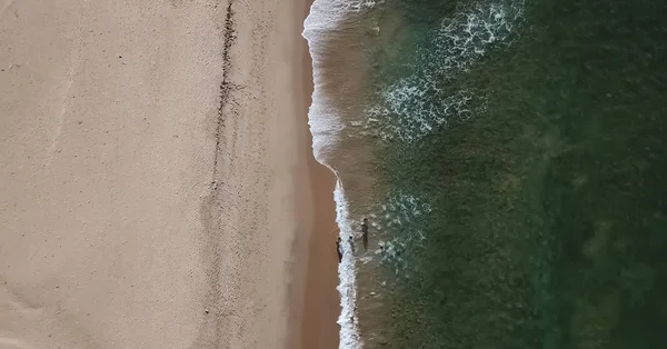 Aerial view, shot with drone on the coast of Angola, people inside water with waves on the beach — Stock Photo, Image