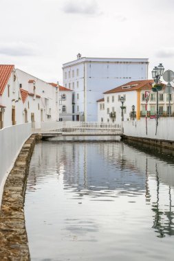 Şehir merkezindeki Tomar şehrinde bir nehir manzarası, yaya köprüsü ve Portekiz kıyılarındaki binalar.