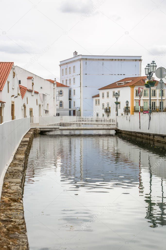 View of a river on Tomar city downtown, pedestrian bridge and buildings on banks, Portugal