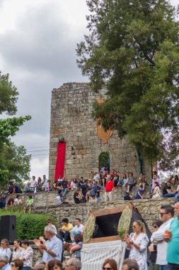 Arka plan olarak Vouzela Ortaçağ panayırı, Ortaçağ şatosundaki açık hava konserini izleyen insanlar görülüyor.