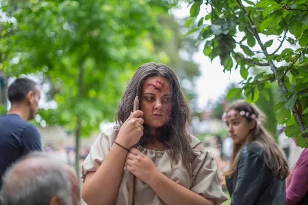 Veduta di un'attrice, malata e vestita in abiti medievali sul mercato medievale, bastone sulle mani, sfondo sfocato — Foto Stock