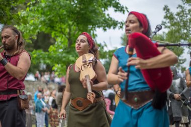 Ortaçağ kıyafetleri içinde ortaçağ enstrümanları çalan müzisyenlerin, ortaçağ fuarında seyircilerin izlediği açık hava Kelt müzik konseri