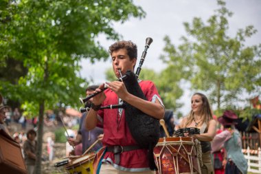 Ortaçağ kıyafetleri içinde ortaçağ enstrümanları çalan müzisyenlerin, ortaçağ fuarında seyircilerin izlediği açık hava Kelt müzik konseri