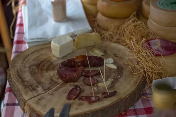 Vista detalhada de uma mão cortando chouriço de porco caseiro e queijo na mesa de madeira — Fotografia de Stock