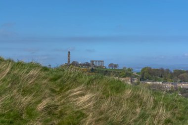 Holyrood Parkı 'ndan Edinburgh şehir merkezine genel hava manzarası, arka planda anıt binalar, dağlar ve parklar