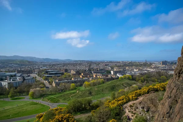 Vista aérea general desde el Holyrood Park hasta el centro de Edimburgo, edificios monumentales, montañas y parques en el fondo — Foto de Stock
