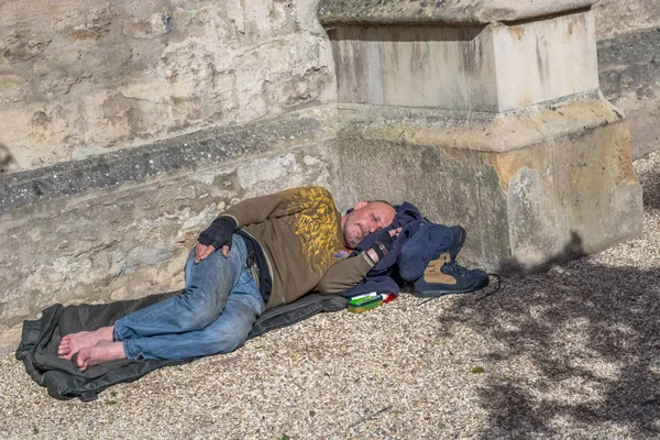 Blick auf einen Obdachlosen, der in der Ecke eines Gebäudes auf der Straße liegt — Stockfoto