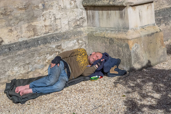 View of homeless man lying in the corner of a building, on the street