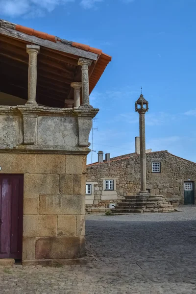 View at the medieval village inside fortress castle of Castelo Mendo, plaza with pillory and medieval buildings