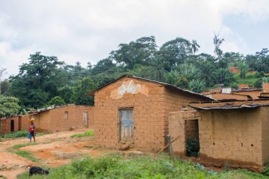 Gabela / Kwanza Sul / Angola - 02: 25 2020: Geleneksel köy manzarası, çatı evleri ve terasotta tuğla duvarlarında sazlık ve çinko çarşaf, Angola 'da elinde leğen ve kova taşıyan kadın