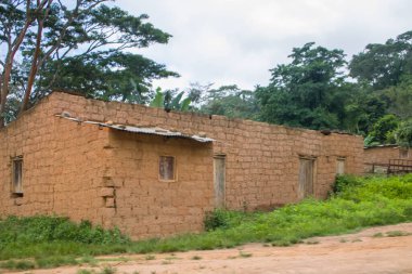 Gabela / Kwanza Sul / Angola - 02 25 2020: Angola 'da geleneksel köy manzarası, çatı evleri ve terasotta tuğla duvarları üzerinde sazlık ve çinko çarşaf, arka plan olarak bulutlu gökyüzü