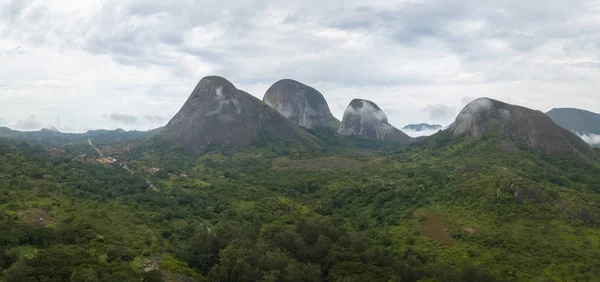 Orman ve dağlarla dolu tropikal bir arazinin hava fotoğrafçılığı, Kumbira Ormanı rezervi, muazzam jeolojik kaya elementleri, arka plan olarak bulutlu gökyüzü, Conda, Sumbe, Angola