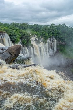 Lucala nehrindeki Kalandula şelalesinin manzarası, tropikal orman ve Angola 'daki bulutlu gökyüzü.