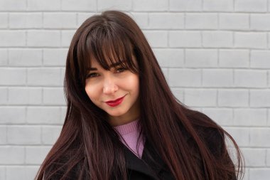 Gri tuğla duvarın arkasında güzel bir esmer.