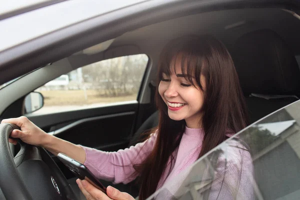 A Happy brunette in a car with a phone