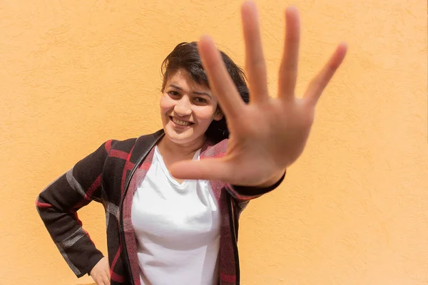 Mulher Feliz Acena Sua Mão Para Câmera Contra Fundo Laranja — Fotografia de Stock