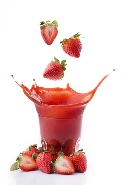 Jordgubbar falla i ett glas juice — Stockfoto