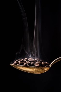 koyu arka plan üzerine bir kaşık sıcak kahve çekirdekleri