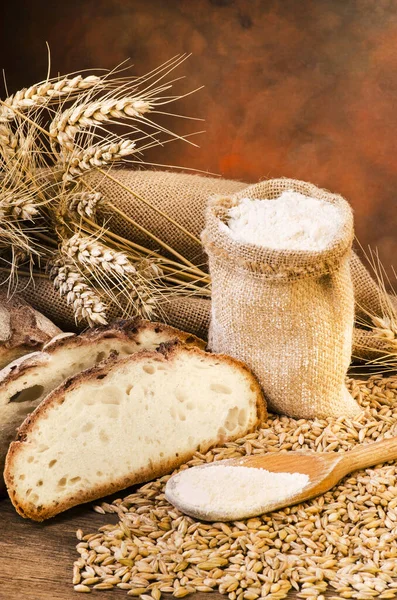 Natura morta Pagnotta di pane con chicchi di grano e farina — Foto Stock
