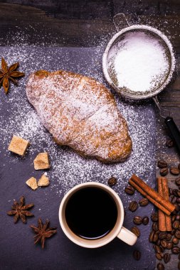 Kahverengi şeker ve sıcak kruvasanla tatlandırılmış bir fincan sade kahveyle kahvaltı.