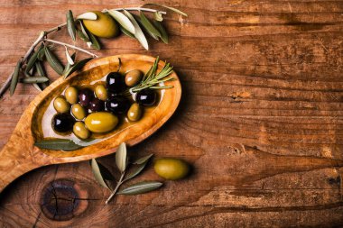 Kırsal ahşap masada, içinde çeşitli zeytin çeşitleri olan bir kase.