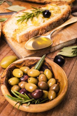 Kırsal ahşap masada, bir kaşık dolusu yağ biraz zeytin ve dilimlenmiş ekmek.