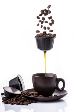 Kavramsal. Kahve kapsülünden sıcak espresso fincana akıyor.