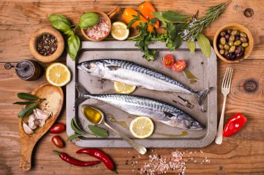 Kırsal ahşap masadaki malzemelerle pişirmeye hazır taze deniz balığı.