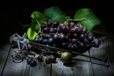 Sert ahşap bir masada eski bir çelik bahçesinde siyah üzümlerle dolu bir hayat