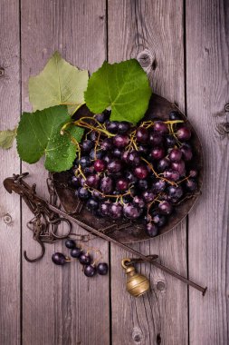 Sert ahşap bir masada eski bir çelik bahçesinde siyah üzümlerle dolu bir hayat