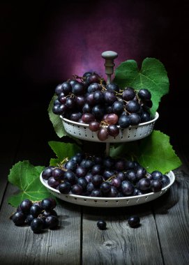 Kırsal ahşap bir masada, siyah üzümlü, sanatsal bir hayat.